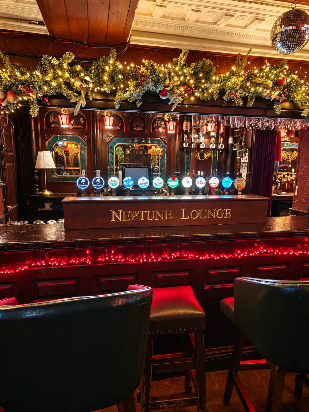 The Neptune Lounge bar downstairs at The Flowing Tide, with red lighting and festive garlands